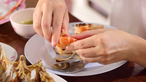 hands methodically peeling shrimp on a plate