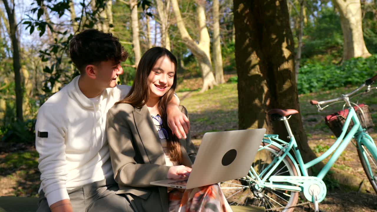 Couple using laptop outdoors with bicycle