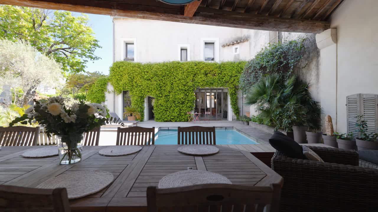 Slow establishing shot of a beautiful villa garden with a pool and furniture