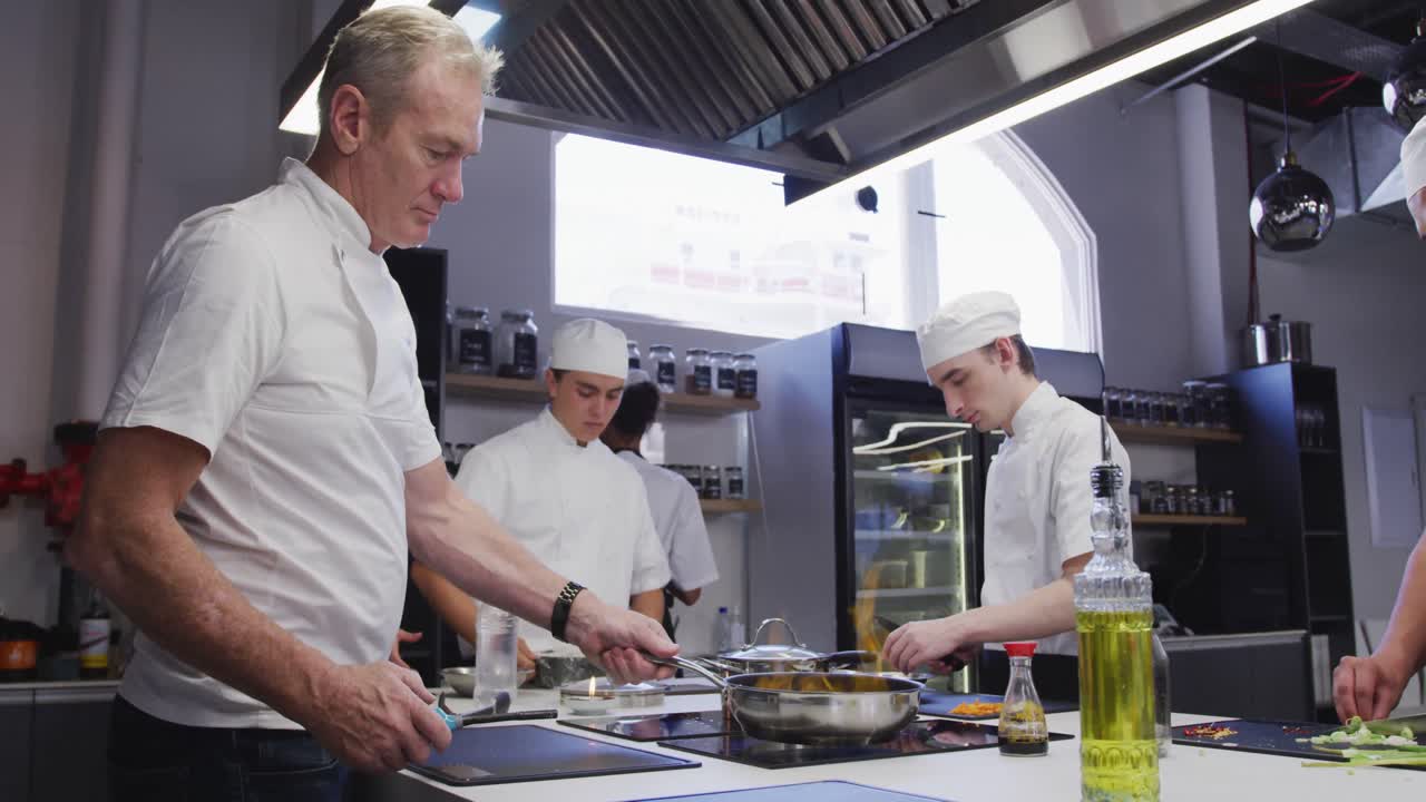 chef masculino caucásico profesional en una cocina de un restaurante preparando comida usando una sartén