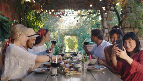 summer dinner party with friends eating mediterranean food sitting at table outdoors chatting enjoying feast 4k footage