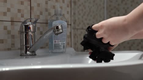 hands of young woman throwing latex gloves and wash hands in the sink