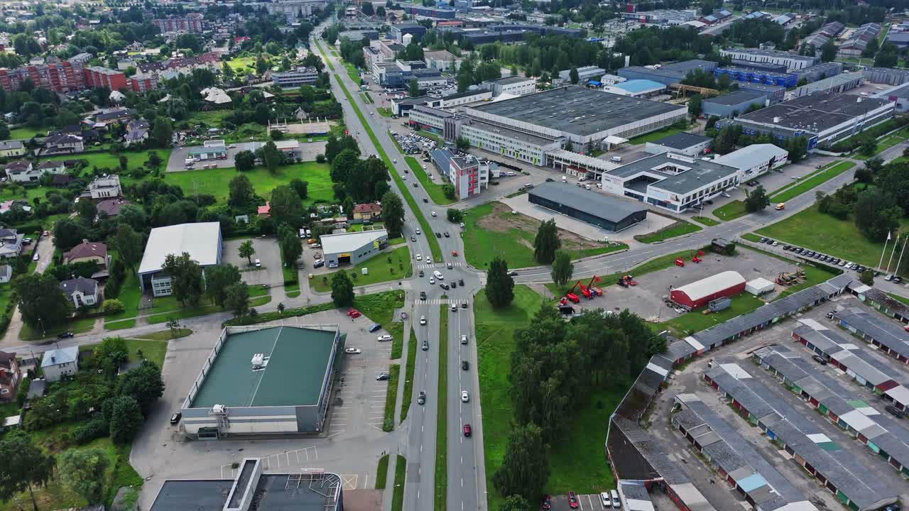 Busy traffic flows along a wide street flanked by factories in Darzciems’ industrial zone