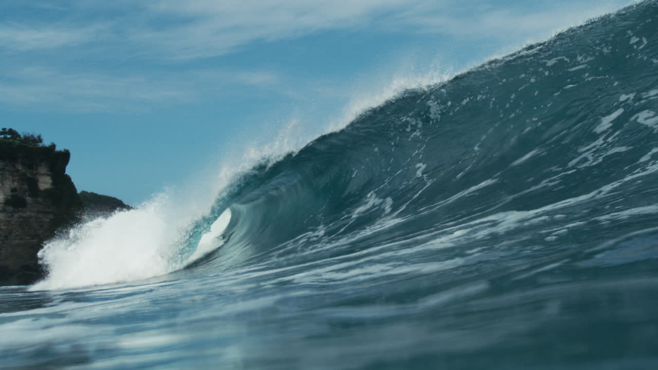 Turquoise wave curls cleanly in bright tropical light, smooth slow motion