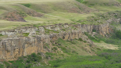 Writing-on-Stone-Provincial-Parks-bandlands-and-Hoodoos-with-river-in-a-desert-in-Alberta,-Canada-during-overcast-day-at-a-distance