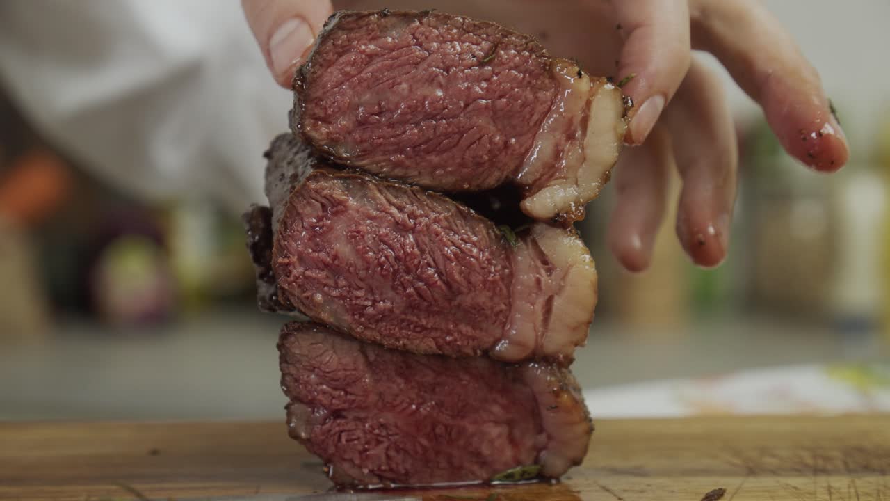 el chef apila trozos de carne de bistec uno encima del otro, formando una torre de bistec