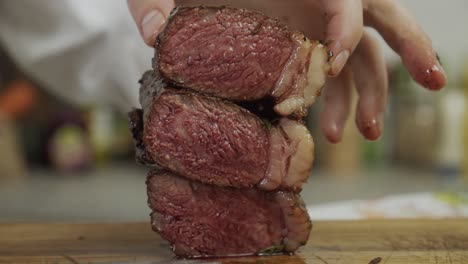 chef stacks steak meat pieces on top of each other, making steak tower