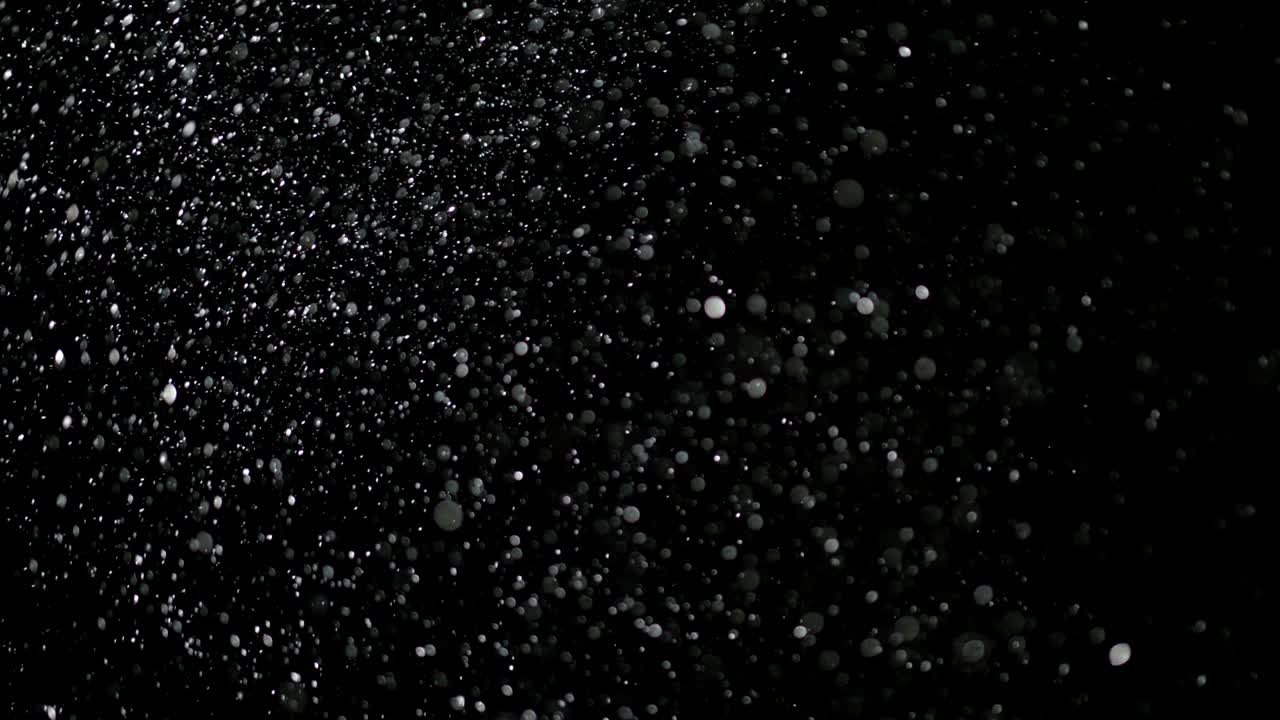 Hidastettu lumi mustalla taustalla.