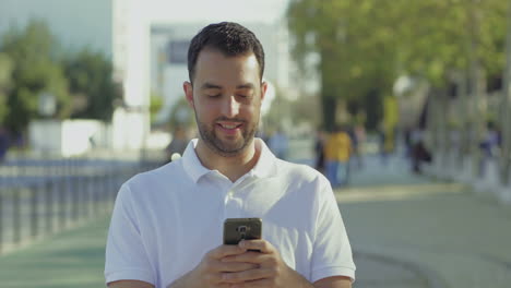 una joven morena sonriente usando un teléfono inteligente al aire libre.