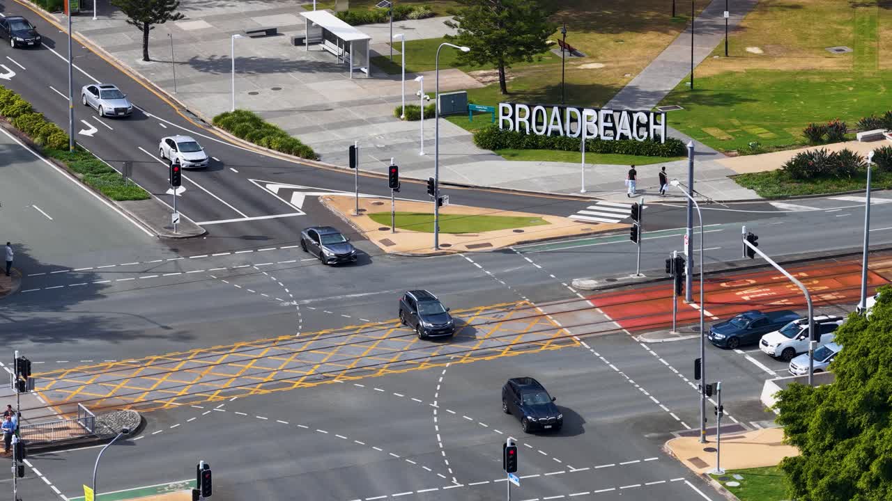 Aerial view of vehicles and trams navigating a busy Broadbeach intersection under clear daylight