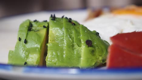 close-up of sliced avocado with sesame seeds on a plate