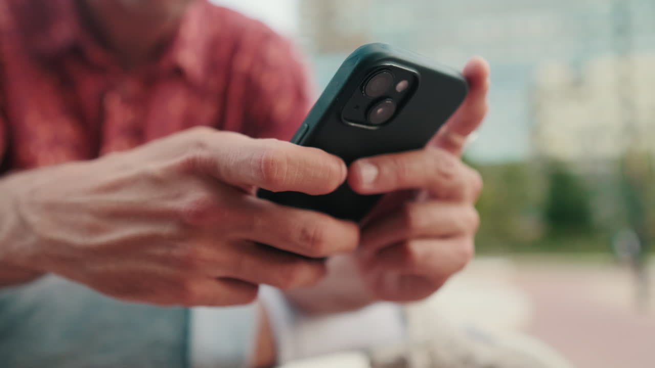 Close-up of Man's Hands Using a Smartphone Outdoors