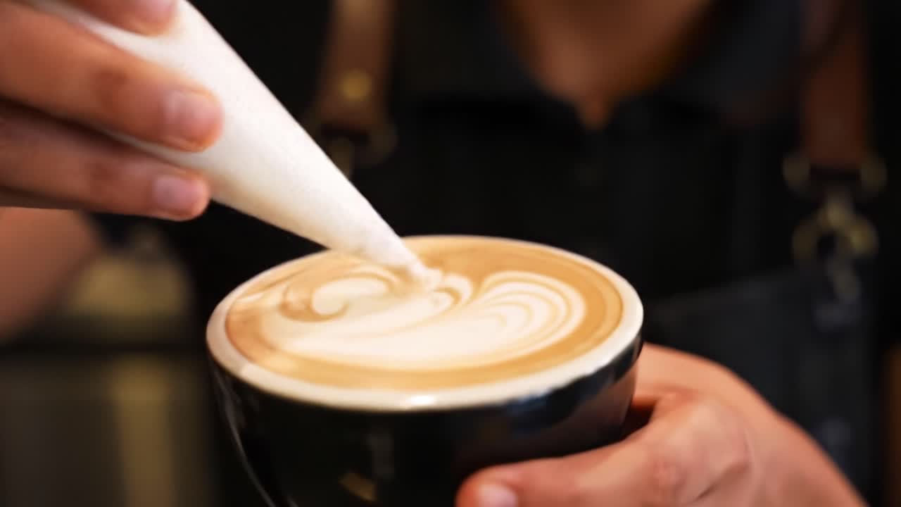 Mastering the Art of Coffee: An Expert Barista Crafts a Beautiful Latte with Intricate Foam Designs for a Perfect Espresso Experience