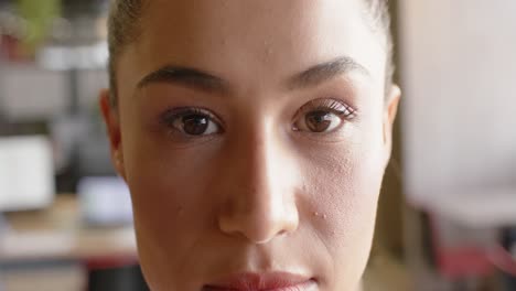 portrait of happy biracial businesswoman looking at camera and smiling at office, slow motion