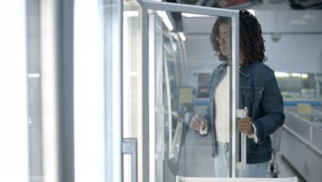 focused young woman choosing goods from fridge