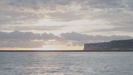 Timelapse-De-4k-Del-Sol-Saliendo-Detrás-De-Las-Nubes-En-El-Mar-Mediterráneo-Con-La-Montaña-Al-Fondo