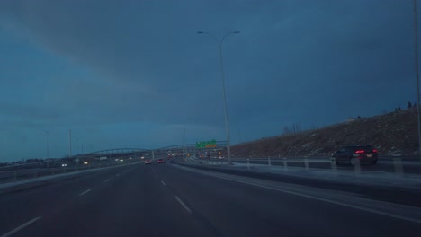 Highway-car-view-passing-under-bridge-at-evening-in-Calgary,-Alberta,-Canada