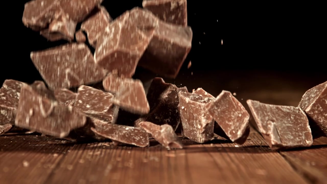 Pezzi di cioccolato che cadono su un tavolo di legno al rallentatore