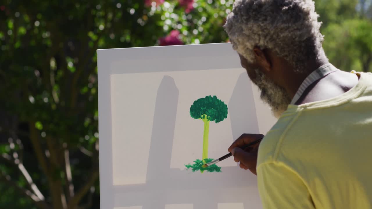 Senior african american man painting picture on a canvas in sunny garden