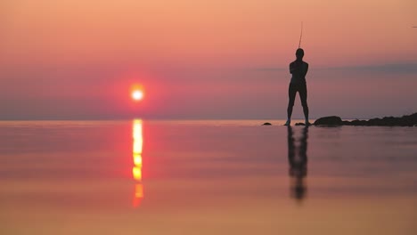 woman fishing on fishing rod spinning at sunset background.