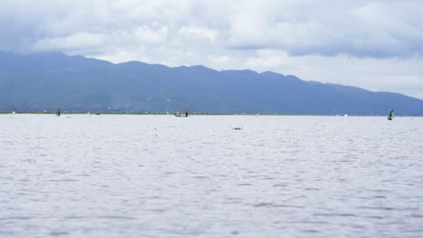 fishermen and mountainside reflection on inle lake, myanmar