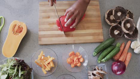 Overhead-view-of-hands-of-african-american-woman-chopping-vegetables-in-kitchen,-slow-motion