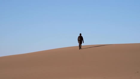 man walking on sand dunes in slow motion