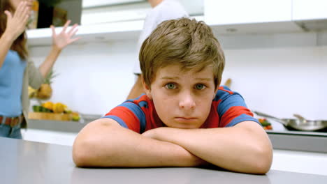 Sad-boy-with-arms-folded-while-parents-quarreling