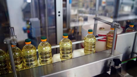 sunflower oil plant indoors. plastic bottles full of yellow oil moving on the conveyor line inside the modern factory background.