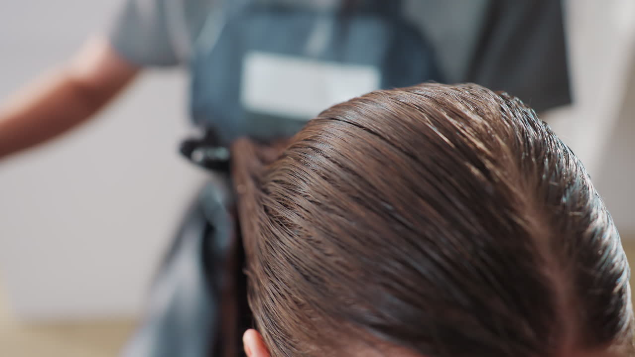 스타일리시한 머릿결 정돈, 헤어 트리트먼트 클로즈업, 전문 스타일리스트가 갈색 머리를 정성스럽게 스타일링, 살롱에서 녹색 브러시로 헤어라인을 부드럽게 다듬는 스타일리스트를 포착한 클로즈업 이미지