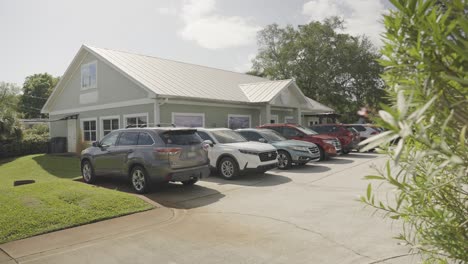 a cinematic view over the tress displaying vehicles parked outside a residential property.