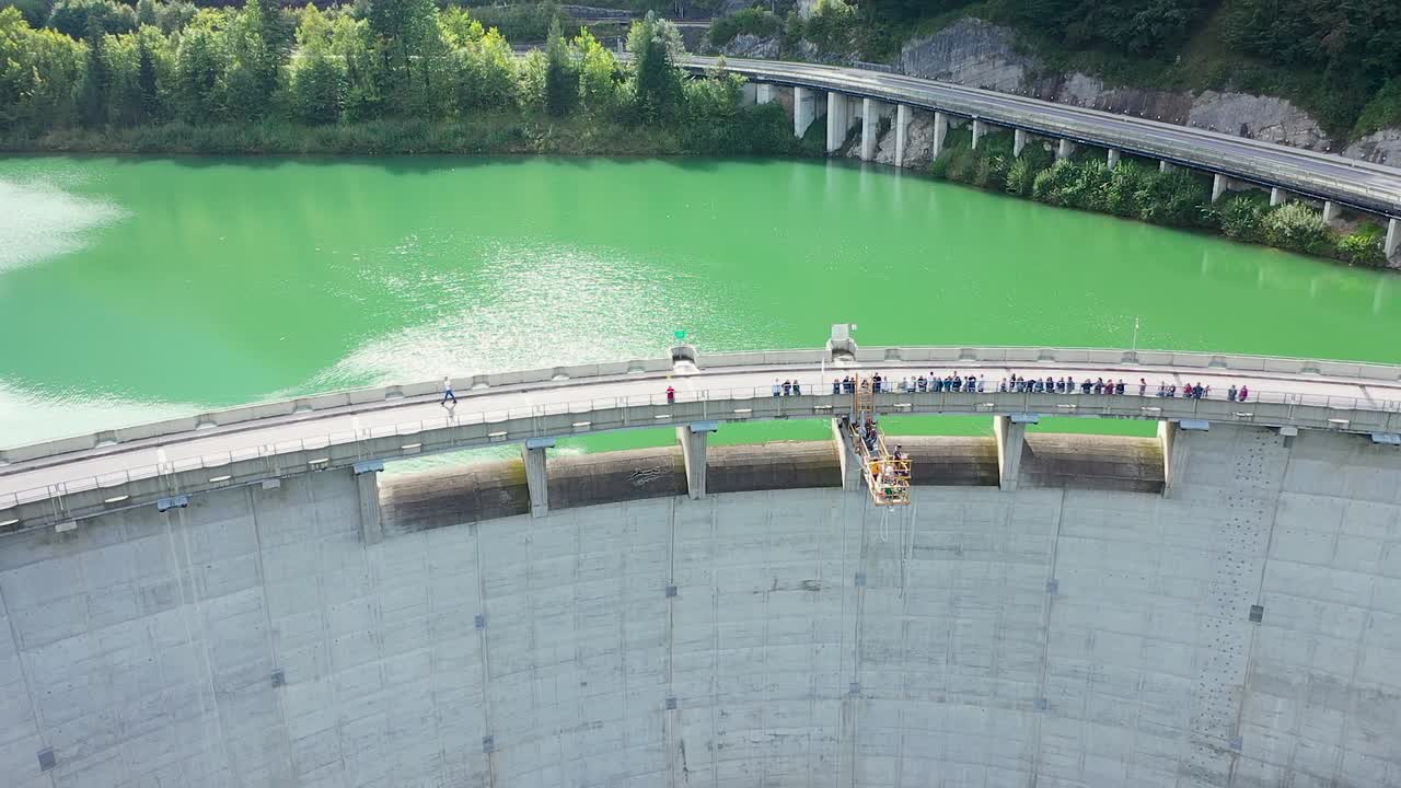 Aerial drone view of bungee jumping dam platform 50m high , viewers standing on dam bridge watching action happen