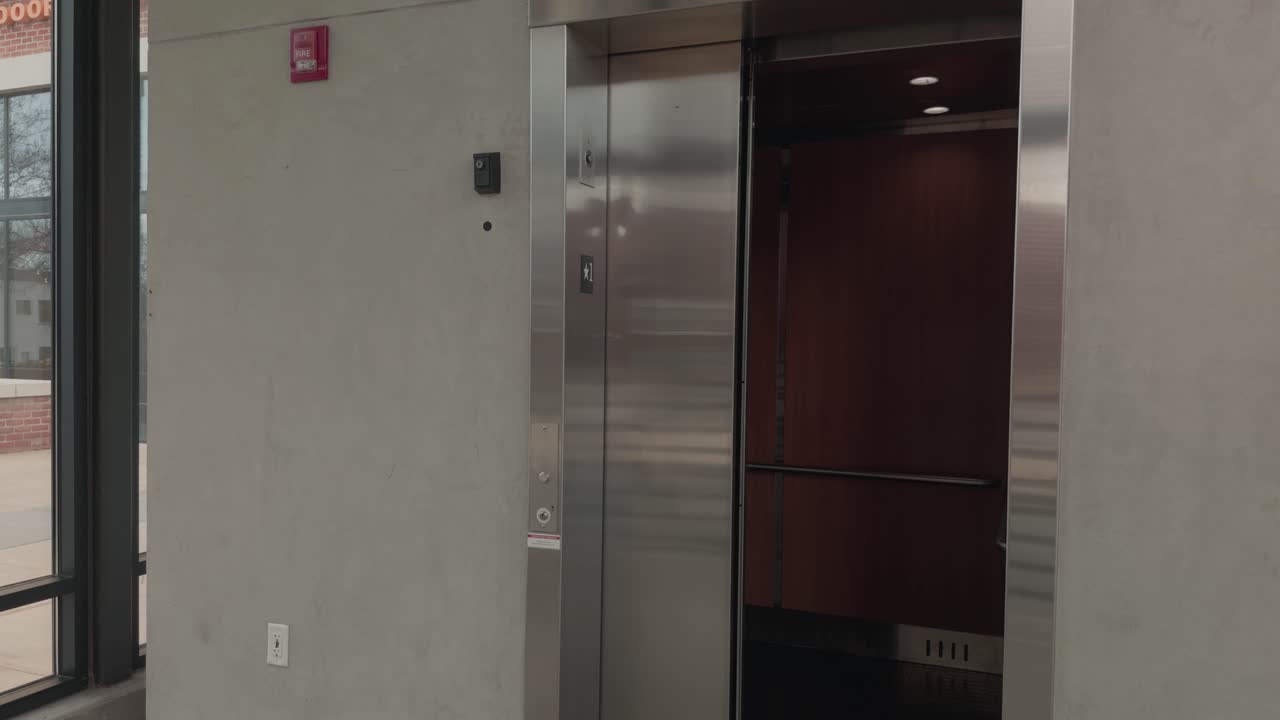 Câmera lenta constante com recuo enquanto as portas do elevador se fecham dentro de um edifício moderno e silencioso