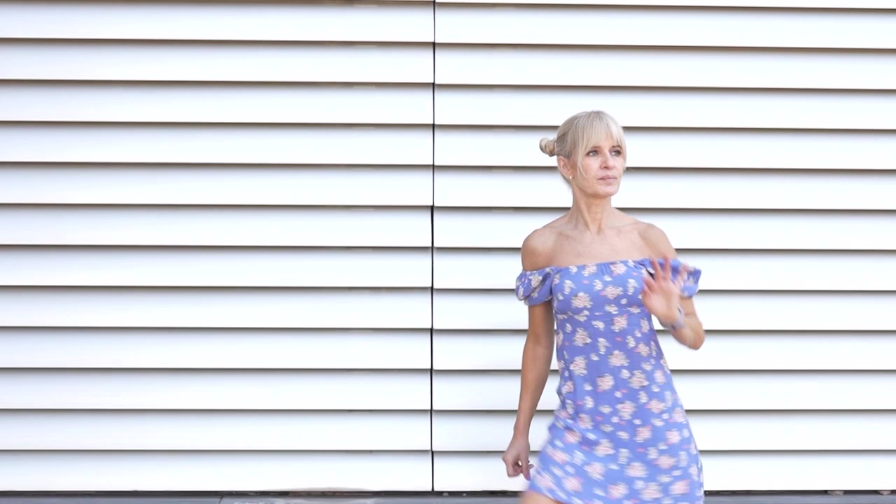 Una donna che indossa un abito floreale in posa all'aperto, emanando eleganza e stile.