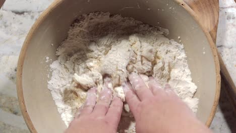 overhead view of kneading eggs and flour into pasta dough