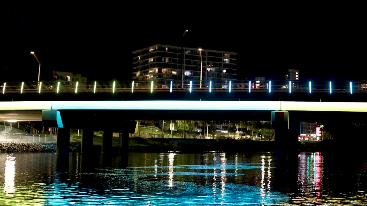 puente y reflejos en la costa dorada por la noche
