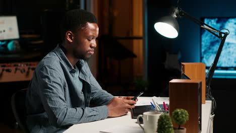 portrait of african american guy scrolling on his mobile phone at home