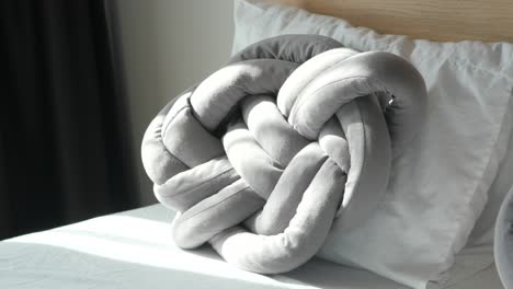 grey knotted pillow on a bed