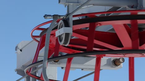 Extreme-Close-Up-of-Red-Ski-Lift-Wheel-Turning-with-Gondola-Chairs-Rotating