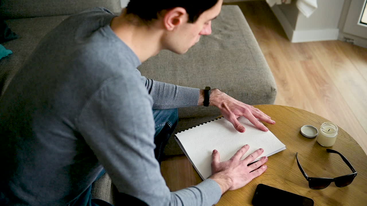 Blind Man Reading A Braille Book While Sitting On Sofa At Home 3