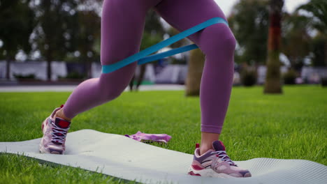 mujer haciendo ejercicios para las piernas con bandas de resistencia en un parque