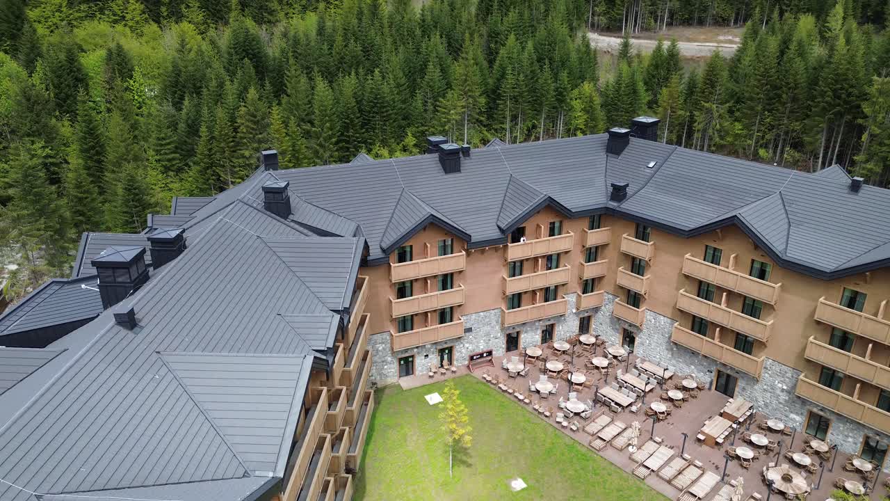 Swissotel resort in Kolasin valley surrounded by lush pine forest in summer, Drone shot
