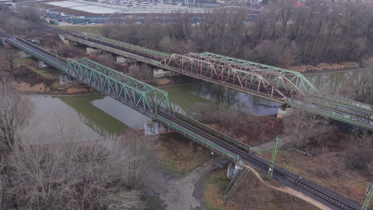 Aerial view of multiple railway bridges crossing a river near an urban industrial area