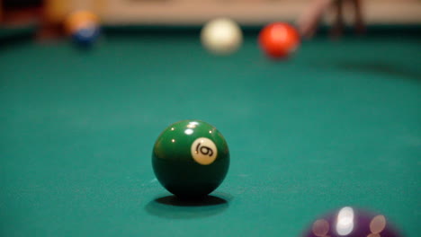 Billardspieler-In-Zeitlupe-Adressiert-Und-Schießt-Gelben-Streifen-9-Ball-Im-Hintergrund-Auf-Billardtisch-Mit-Grünem-Filz-Mit-Schwarzem-Kohlefaser-Queue-Stick,-Während-Er-über-5-Bälle-In-Der-Nähe-Der-Schärfentiefe-überbrückt