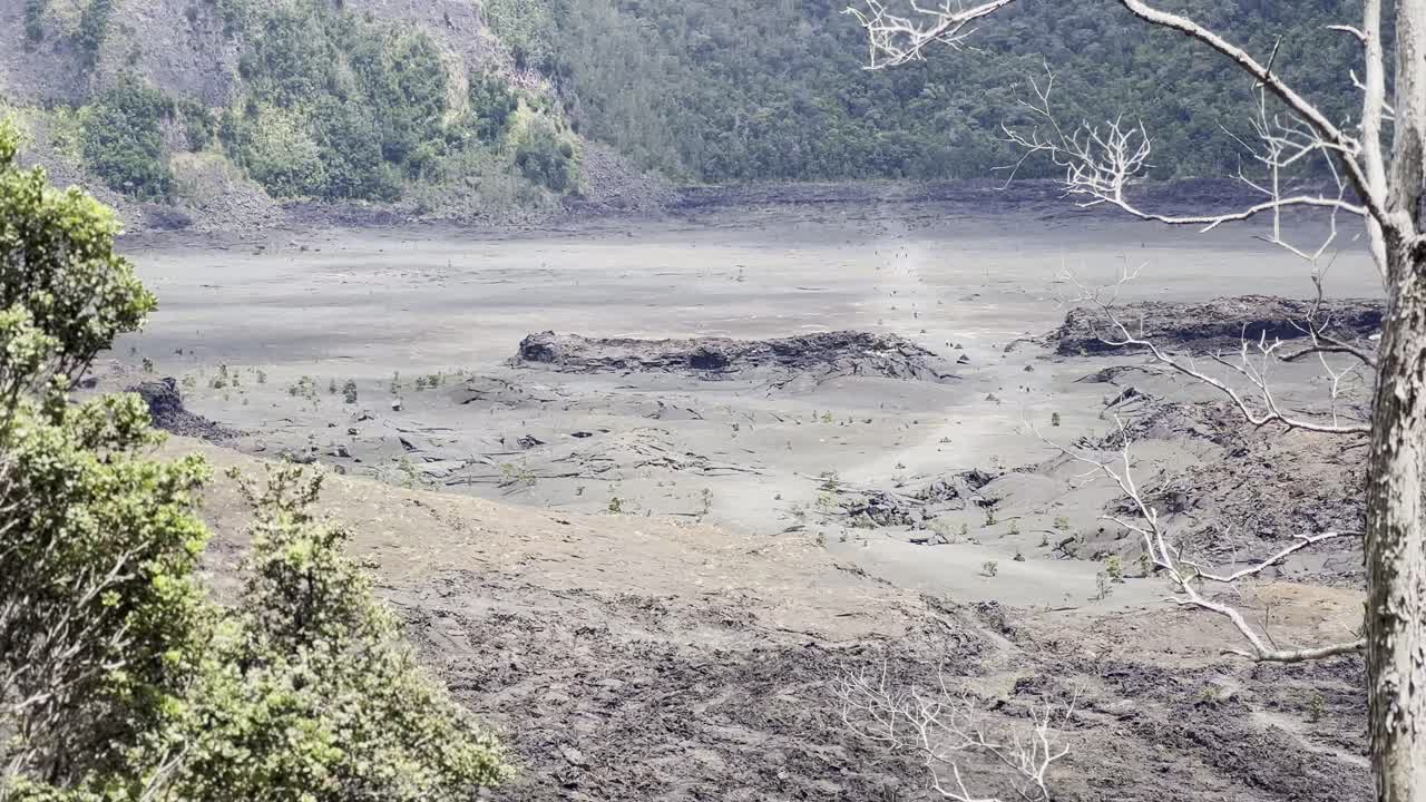 Cinematic long lens booming down shot of the dry lava lake bed at Kilauea Iki from an overlook in Hawai'i Volcanoes National Park
