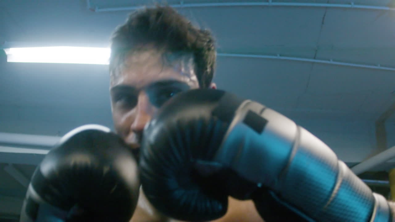 Giovane uomo attraente che fa shadow boxing verso la telecamera