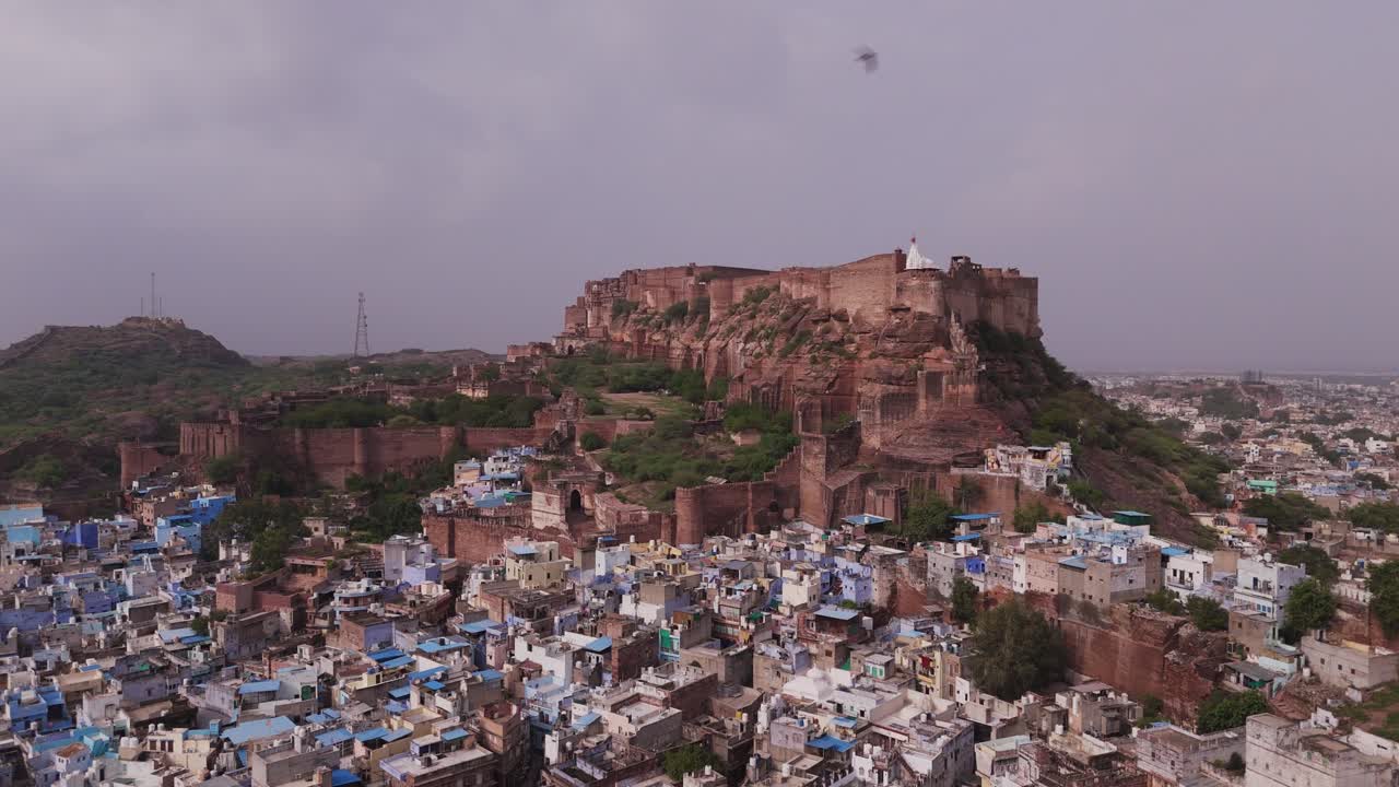 Jodhpur, the blue city, with the majestic Mehrangarh Fort in background. Drone aerial fly over late afternoon.