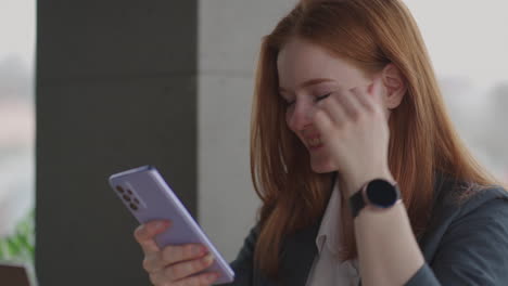 Young businesswoman use smart phone with laptop. Business woman in a modern office with a panoramic window sunny day laptop tablet use a mobile phone in a situation