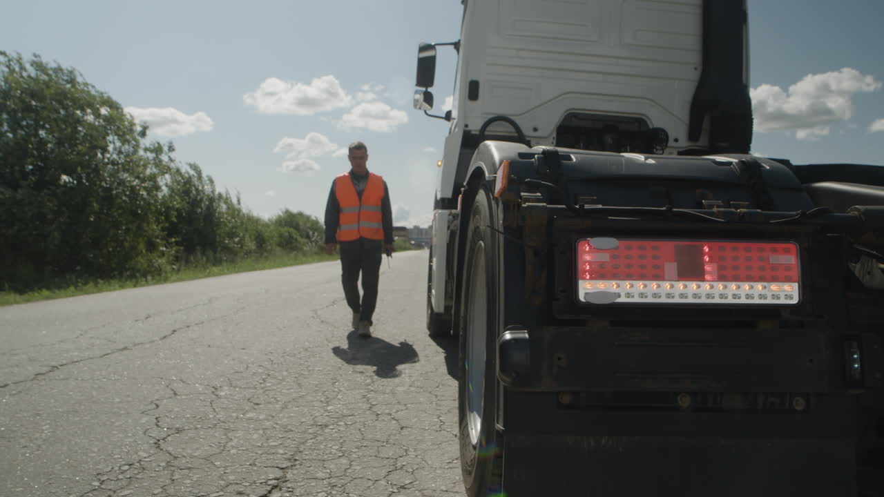 Truck Driver Inspecting Tires on Road