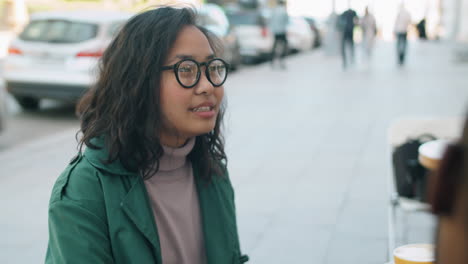 Mujer-Asiática-Hablando-Con-Un-Colega-Masculino-En-Un-Café-Al-Aire-Libre